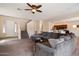Open-concept living room featuring carpet flooring, stairs, ceiling fan and a large comfortable sectional sofa at 973 E Corral St, Avondale, AZ 85323
