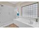 Bright bathroom featuring a glass enclosed shower, soaking tub, and large window with decorative glass blocks at 13450 E Via Linda -- # 2022, Scottsdale, AZ 85259
