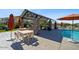 Poolside patio includes a covered area with stone pillars, tables, lounge chairs, and umbrellas for relaxing by the water at 14659 W Sand Hills Rd, Surprise, AZ 85387