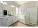 Bright bathroom features a double sink vanity, soaking tub, and glass-enclosed shower at 15088 W Coolidge St, Goodyear, AZ 85395