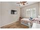 Cozy bedroom featuring wood floors, a ceiling fan, and a window with plantation shutters at 15088 W Coolidge St, Goodyear, AZ 85395