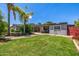 Lush backyard with green grass, a covered patio, and mature palm trees create a serene oasis at 253 N Fraser Dr, Mesa, AZ 85203