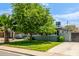Well-maintained single-Gathering home with a lush green lawn and mature trees providing shade at 253 N Fraser Dr, Mesa, AZ 85203