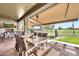 Spacious covered patio with a dining area, fireplace, and views of the manicured backyard with water feature at 6131 S Bradshaw Way, Chandler, AZ 85249