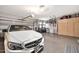 Well-lit garage showcasing a white car, golf cart, epoxy flooring, and ample storage space at 6131 S Bradshaw Way, Chandler, AZ 85249