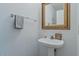 Charming powder room featuring a pedestal sink, decorative mirror, and a towel rack, offering a stylish and functional space at 6321 W Gross Ave, Phoenix, AZ 85043