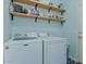 Functional laundry room with washer, dryer, and open shelving for storage at 6321 W Gross Ave, Phoenix, AZ 85043