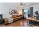 Comfortable living room featuring a brown leather sofa, decorative artwork, and a cozy workspace near the window at 6321 W Gross Ave, Phoenix, AZ 85043