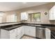 A well-lit kitchen with white cabinets, black countertops, and stainless steel appliances at 7029 S Golfside Ln, Phoenix, AZ 85042