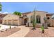Elegant stucco home showcasing a three-car garage, desert landscaping, and a charming arched entryway at 915 W Orchard Ln, Litchfield Park, AZ 85340