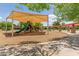 Community playground featuring a shaded play structure, bordered with woodchips and connected by sidewalks at 915 W Orchard Ln, Litchfield Park, AZ 85340
