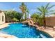 Backyard pool boasts a rock waterfall feature surrounded by lush, tropical landscaping and mature palm trees at 915 W Orchard Ln, Litchfield Park, AZ 85340