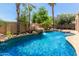 Backyard pool includes rock waterfall feature with tropical landscaping and mature palm trees in the backyard at 915 W Orchard Ln, Litchfield Park, AZ 85340
