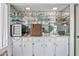 A bar area with white cabinets, mirrored backsplash and shelves with glassware and mini fridge at 9654 E Foster Ave, Sun Lakes, AZ 85248