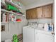 Functional laundry room with a washer, dryer, open shelving, overhead cabinetry, and tile flooring for easy maintenance at 9654 E Foster Ave, Sun Lakes, AZ 85248