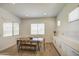 Bright dining area with wooden table, bench, and chairs beside the kitchen with white cabinets and countertops at 9845 E Thistle Ave, Mesa, AZ 85212
