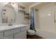 Simple bathroom with white vanity, mirror, open shelving and shower-tub combination with floral shower curtain at 9929 W Thunderbird Blvd, Sun City, AZ 85351