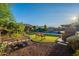Lush backyard with lounge seating near the pool, an outdoor grill, and artificial grass at 10207 W Hedge Hog Pl, Peoria, AZ 85383