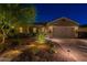 Charming single-Gathering home featuring lush landscaping and warm exterior lighting at night at 10207 W Hedge Hog Pl, Peoria, AZ 85383