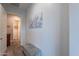Hallway featuring tile floors, gray walls, bench, and view of rooms with artwork at 10207 W Hedge Hog Pl, Peoria, AZ 85383