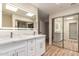 Modern bathroom vanity with double sinks, white cabinets and lighted mirrors at 10318 E Michigan Ave, Sun Lakes, AZ 85248