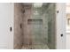 Sleek glass shower with gray tile, niche, and pebble floor at 10318 E Michigan Ave, Sun Lakes, AZ 85248