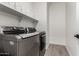 Modern laundry room featuring gray washer and dryer, tile floors, and ample shelving for storage at 128 S 200Th Ave, Buckeye, AZ 85326