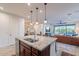 Open kitchen showcasing a granite island with seating, stainless steel appliances, and access to the living room and patio at 13719 W Amberwing St, Peoria, AZ 85383