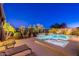 Gorgeous backyard featuring a sparkling pool and spa, surrounded by lush landscaping and a patio with lounge chairs at 13719 W Amberwing St, Peoria, AZ 85383