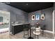 Inviting wet bar area with stylish seating, dark green cabinets, and sleek countertop, perfect for entertaining guests at 14372 W Cypress St, Goodyear, AZ 85395