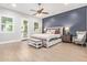 Beautiful primary bedroom with a dark blue accent wall, a ceiling fan, and french doors at 14372 W Cypress St, Goodyear, AZ 85395
