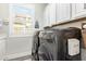 Well-organized laundry room with gray washer/dryer, cabinets, and natural light from the window at 14372 W Cypress St, Goodyear, AZ 85395