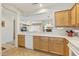 Cozy kitchen features white appliances and light wood cabinets with a view to the living area at 16412 W Peppertree Ct, Surprise, AZ 85387