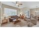 Bright living room with a brown leather sofa, wooden coffee table, and sliding glass door to the patio at 16412 W Peppertree Ct, Surprise, AZ 85387