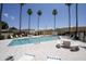 Community pool surrounded by tiled deck, mature palm trees, and comfortable lounge chairs at 17032 N 16Th Dr # 8, Phoenix, AZ 85023