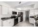 Open kitchen with modern black appliances, white cabinets, and wood-look flooring, featuring a pantry at 19031 N 13Th Dr, Phoenix, AZ 85027
