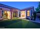 Expansive backyard featuring manicured lawn, multiple entry points to the home, and ambient lighting at 22364 N 59Th Ln, Glendale, AZ 85310