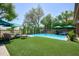 Backyard with pool, turf grass, lounging furniture, and lush plants surrounded by trees in a well-manicured setting at 22364 N 59Th Ln, Glendale, AZ 85310