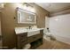 Bathroom featuring a farmhouse sink with white countertops, wooden cabinets, and shower-tub combo with white tile at 22364 N 59Th Ln, Glendale, AZ 85310