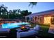 Inviting backyard pool area with lush landscaping, solar panels, and cozy outdoor seating at dusk at 22364 N 59Th Ln, Glendale, AZ 85310