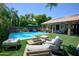 A backyard pool with turquoise water, surrounding lounge furniture, an umbrella and lush trees with beautiful landscaping at 22364 N 59Th Ln, Glendale, AZ 85310