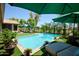 Backyard pool features blue water, poolside furniture, lush landscaping and covered umbrellas on the artificial grass at 22364 N 59Th Ln, Glendale, AZ 85310
