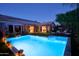 Backyard at dusk showcasing a glowing pool with lounge chairs, lush landscaping, a covered patio and exterior lighting at 22364 N 59Th Ln, Glendale, AZ 85310
