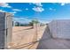 Gravel driveway with chain link gate and cinderblock wall, leading into backyard with utilities at 2261 E Decatur St, Mesa, AZ 85213