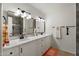 Bright bathroom featuring double sinks, modern fixtures, mirrors, and a shower with decorative tile at 2261 E Decatur St, Mesa, AZ 85213