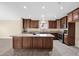 Kitchen featuring an island, tile flooring, granite countertops, dark wood cabinetry, and stainless steel appliances at 2620 E Rustling Oaks Ln, Phoenix, AZ 85024
