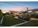 Luxury home featuring a resort-style backyard with pool, bocce court, and lush landscaping at dusk at 4024 E Minton Cir, Mesa, AZ 85215