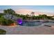 Outdoor pool with rock waterfall slide, lighting, and sun loungers, perfect for relaxing evenings at 4024 E Minton Cir, Mesa, AZ 85215