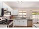 Bright kitchen featuring white cabinets, stainless steel appliances, and a large window overlooking the backyard at 8103 E Dartmouth St, Mesa, AZ 85207