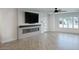 Bright living room featuring an electric fireplace, large TV, ceiling fan, and a window with plantation shutters at 8318 E Sells Dr, Scottsdale, AZ 85251